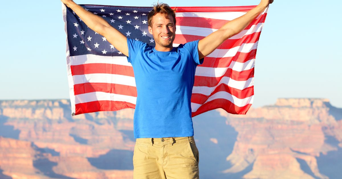 Turista en la cima del Gran Cañón con Bandera Estadounidense