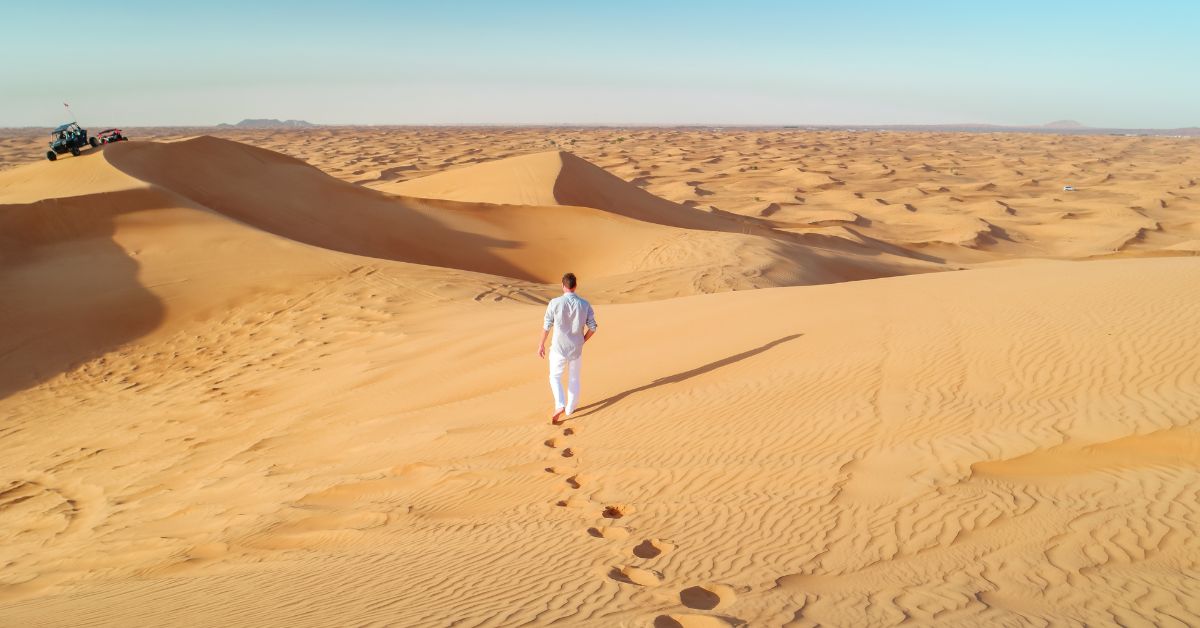 Hombre de Vacaciones camina sobre Dunas de arena en el desierto de Dubái.Safari en las dunas rojas de Dubái