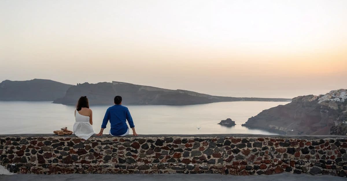 Pareja disfruta de espectacular vista de acantilados y bahía de Santorini, Grecia