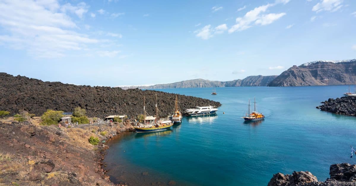 Pintoresco paseo en barco cerca de acantilados volcánicos de Nea Kameni, Santorini