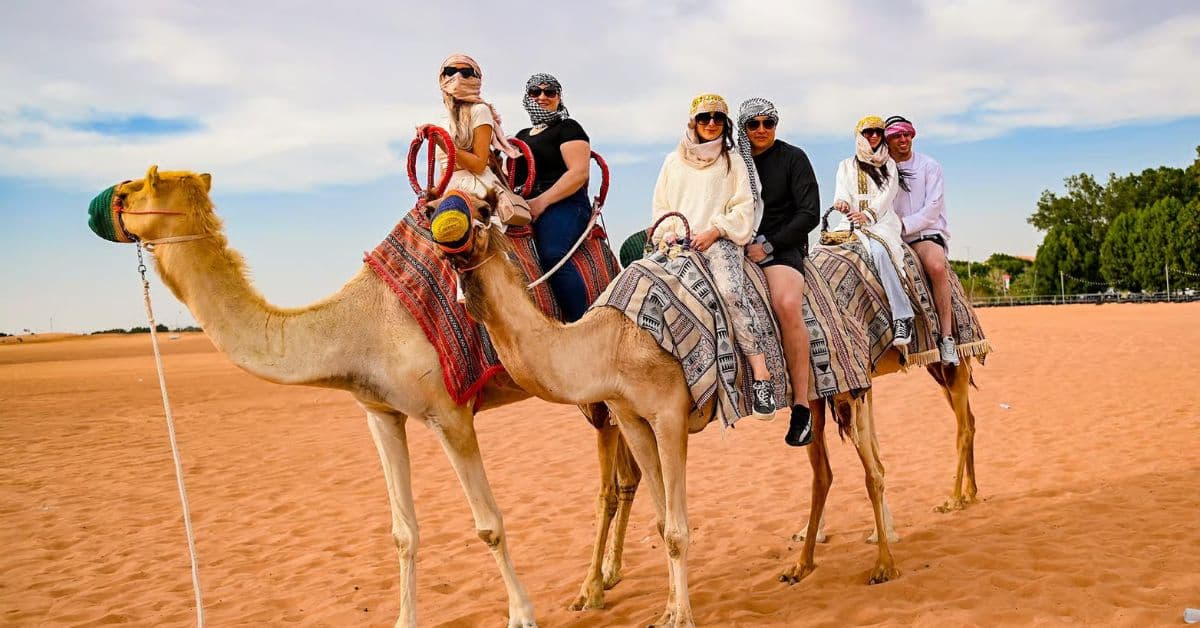 Turistas montan a camello en desierto en Dubái, EAU