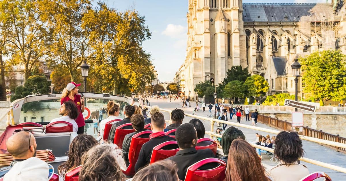 Turistas en bus descapotable recorren avenidas y calles de París, Francia