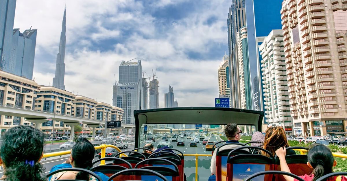 Turistas disfrutas de vistas de Dubái en autobús turístico descapotable