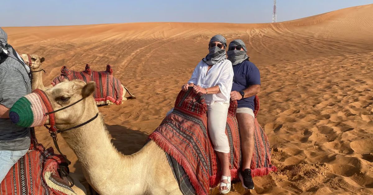 Turistas sobre camellos en Desierto de Dubái, Emiratos Árabes Unidos